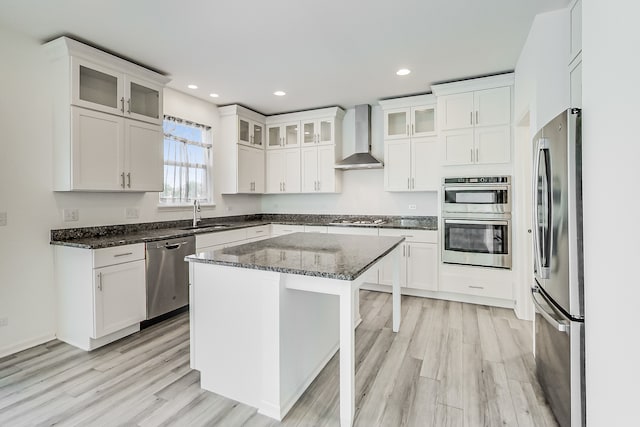 kitchen featuring wall chimney exhaust hood, white cabinetry, stainless steel appliances, and dark stone counters