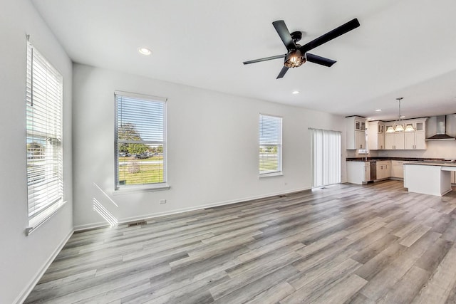 unfurnished living room featuring ceiling fan, light wood-type flooring, and a wealth of natural light