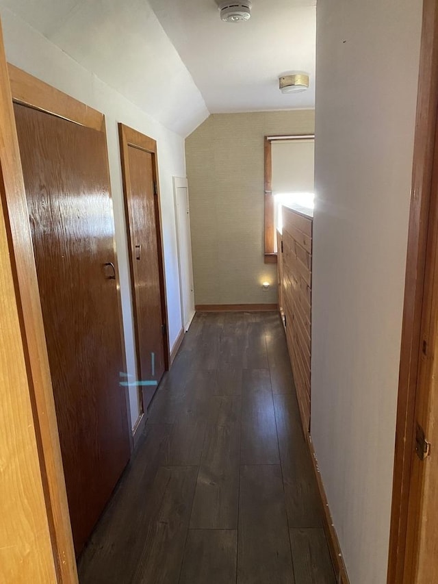 hallway with dark hardwood / wood-style flooring and vaulted ceiling