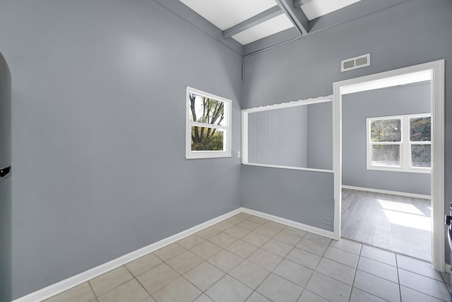 tiled spare room with beamed ceiling and plenty of natural light