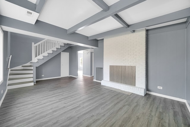 unfurnished living room featuring a brick fireplace, beam ceiling, and dark wood-type flooring