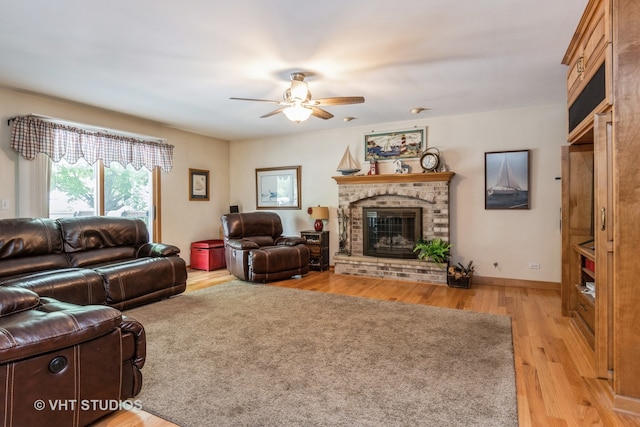 living room with a brick fireplace, light hardwood / wood-style floors, and ceiling fan