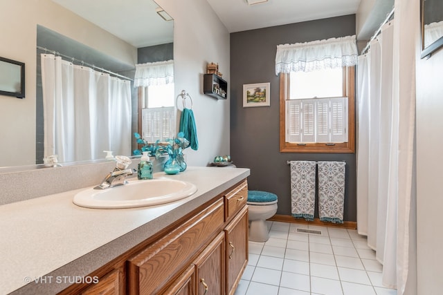 bathroom with tile patterned floors, vanity, a wealth of natural light, and toilet