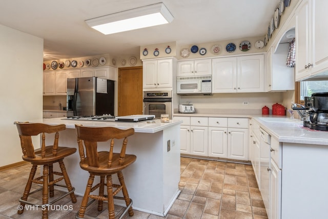 kitchen featuring sink, white cabinetry, stainless steel appliances, a center island, and a kitchen bar