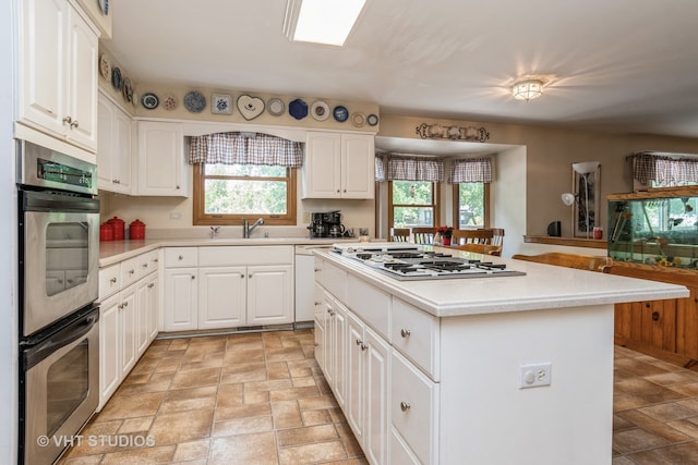 kitchen with stainless steel appliances, plenty of natural light, white cabinetry, and a center island