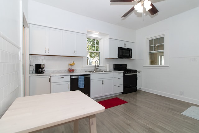 kitchen with ceiling fan, sink, white cabinetry, black appliances, and hardwood / wood-style flooring