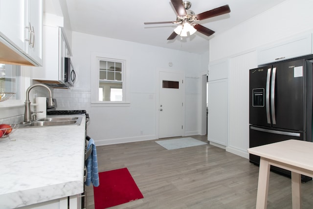 kitchen with refrigerator with ice dispenser, backsplash, light hardwood / wood-style floors, and white cabinets