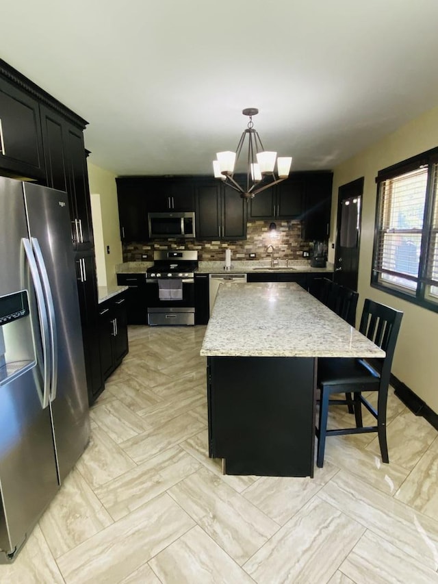 kitchen featuring sink, a center island, a notable chandelier, pendant lighting, and appliances with stainless steel finishes