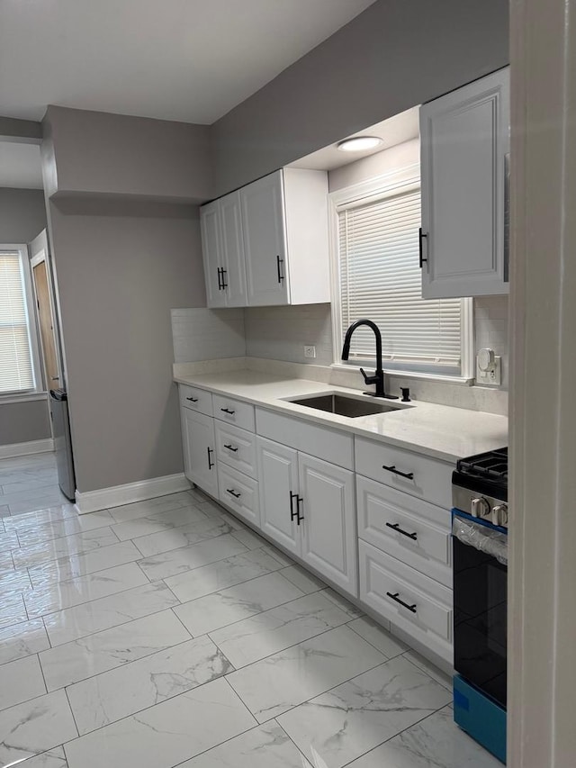 kitchen featuring plenty of natural light, white cabinetry, sink, and stainless steel range