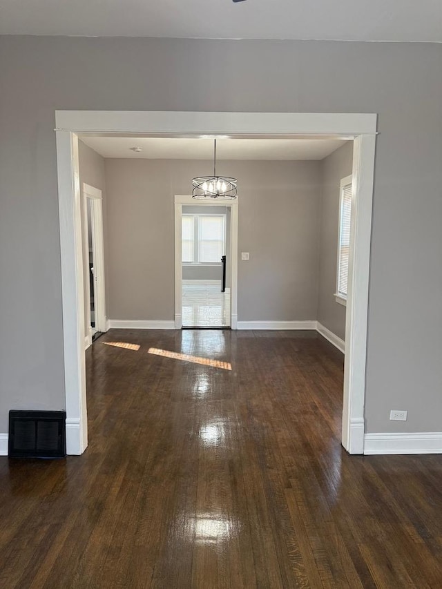 unfurnished dining area with dark hardwood / wood-style floors and a notable chandelier