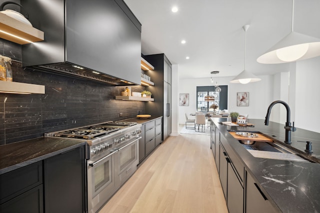 kitchen featuring high end stainless steel range, hanging light fixtures, backsplash, and wall chimney range hood