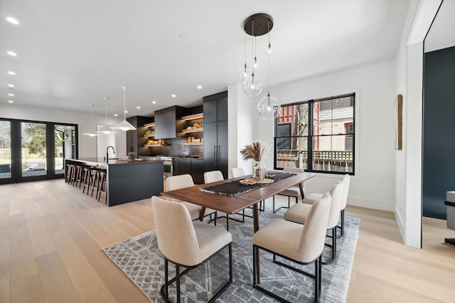 dining area with french doors, light wood-type flooring, plenty of natural light, and sink