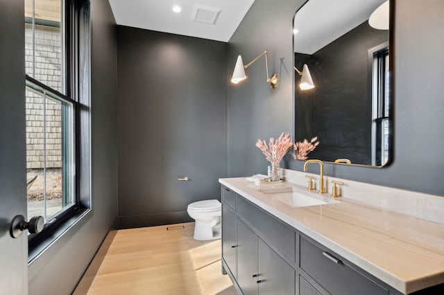 bathroom with wood-type flooring, vanity, and toilet