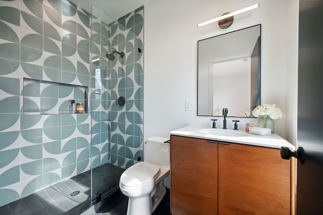 bathroom featuring vanity, tile patterned flooring, toilet, and tiled shower