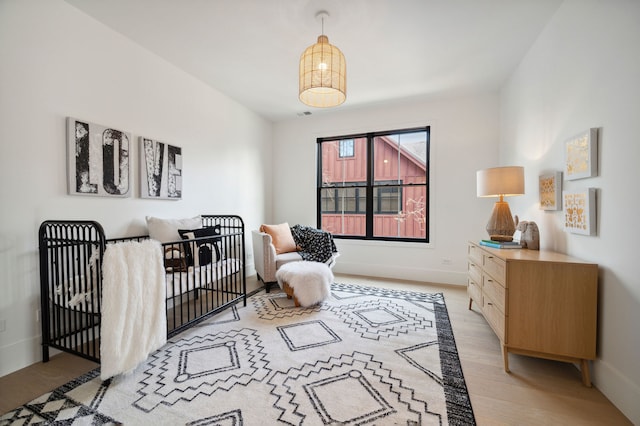 bedroom with light hardwood / wood-style flooring and a nursery area