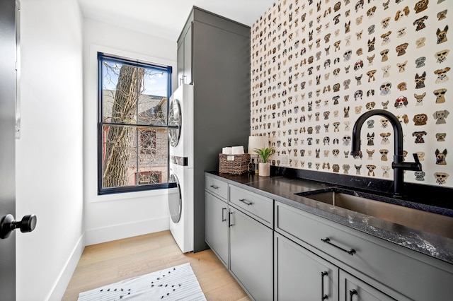 kitchen featuring gray cabinetry, light wood-type flooring, sink, and dark stone counters