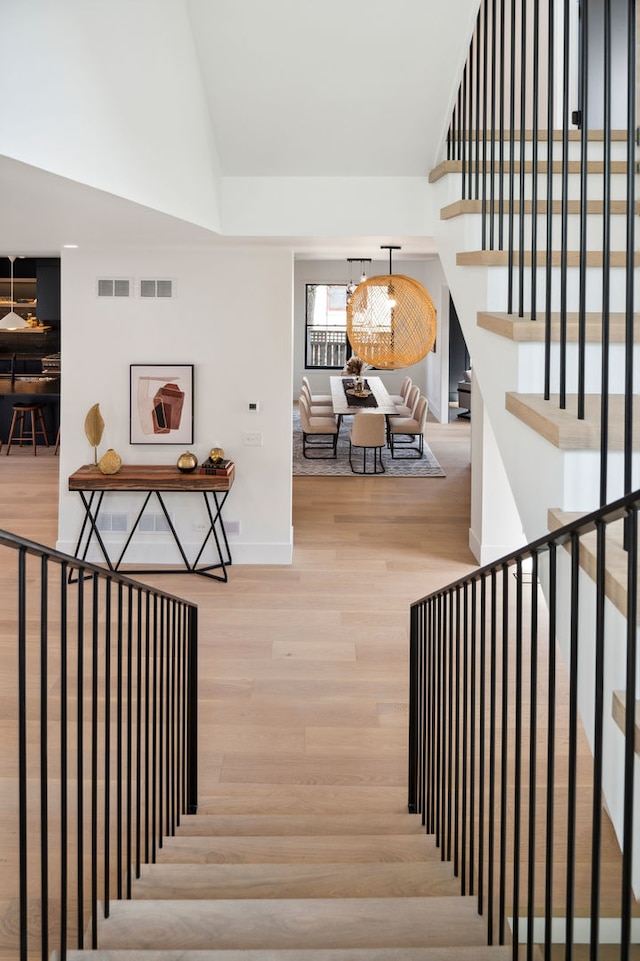 staircase featuring wood-type flooring and a chandelier