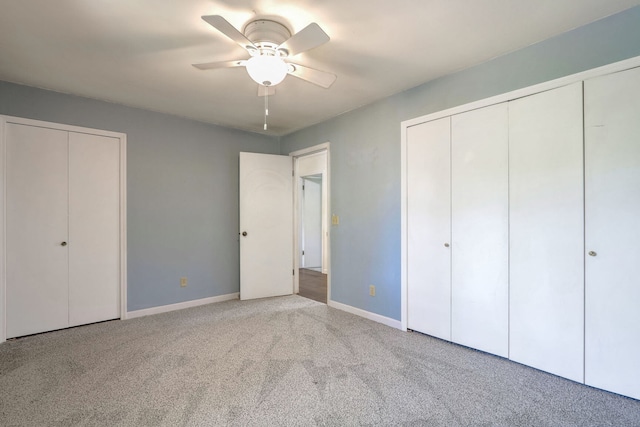 unfurnished bedroom with multiple closets, light colored carpet, and ceiling fan