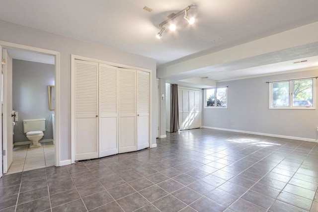 unfurnished bedroom with a closet, ensuite bath, and tile patterned flooring