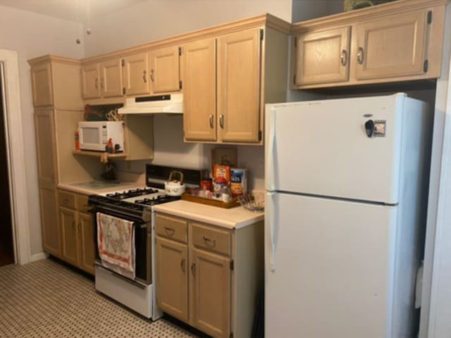 kitchen with light countertops, under cabinet range hood, and white appliances