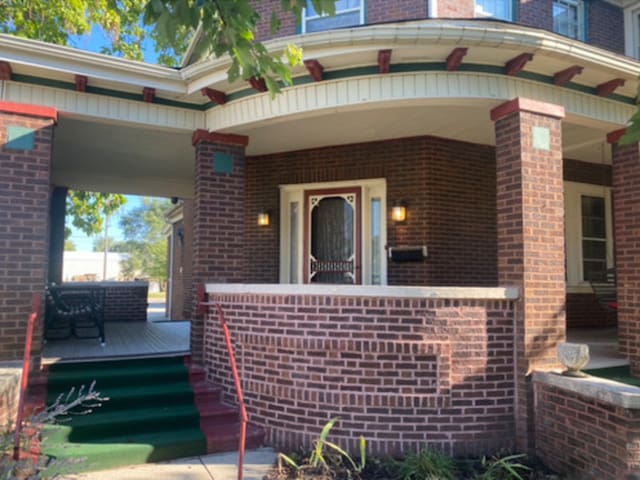 entrance to property featuring covered porch and brick siding