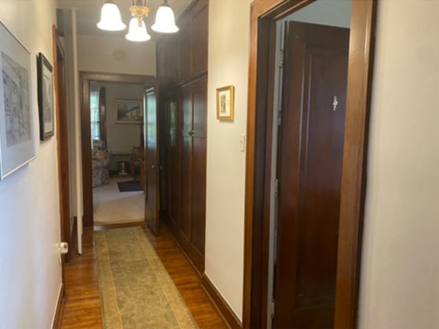 corridor with an inviting chandelier and dark hardwood / wood-style flooring