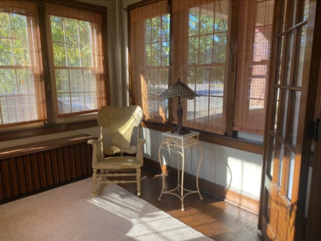 sunroom / solarium featuring wood finished floors, baseboards, and radiator