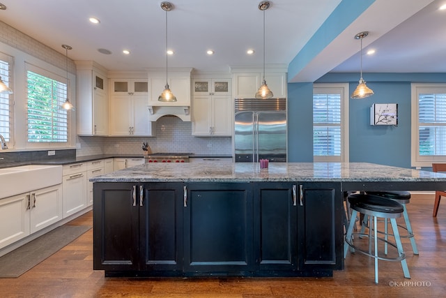 kitchen featuring sink, wood-type flooring, decorative light fixtures, stainless steel appliances, and a center island