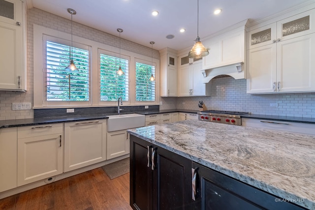 kitchen with dark hardwood / wood-style floors, white cabinetry, sink, and pendant lighting