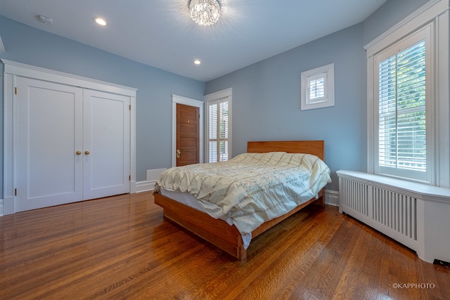 bedroom with radiator heating unit and dark hardwood / wood-style floors