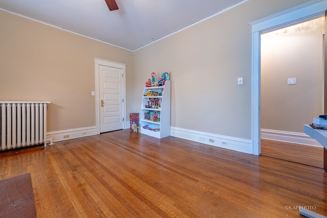 spare room with ornamental molding, ceiling fan, radiator heating unit, and hardwood / wood-style flooring