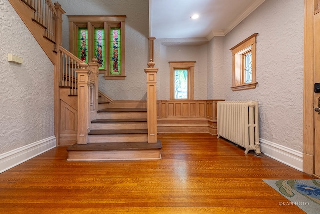 stairs featuring ornamental molding, hardwood / wood-style floors, and radiator heating unit