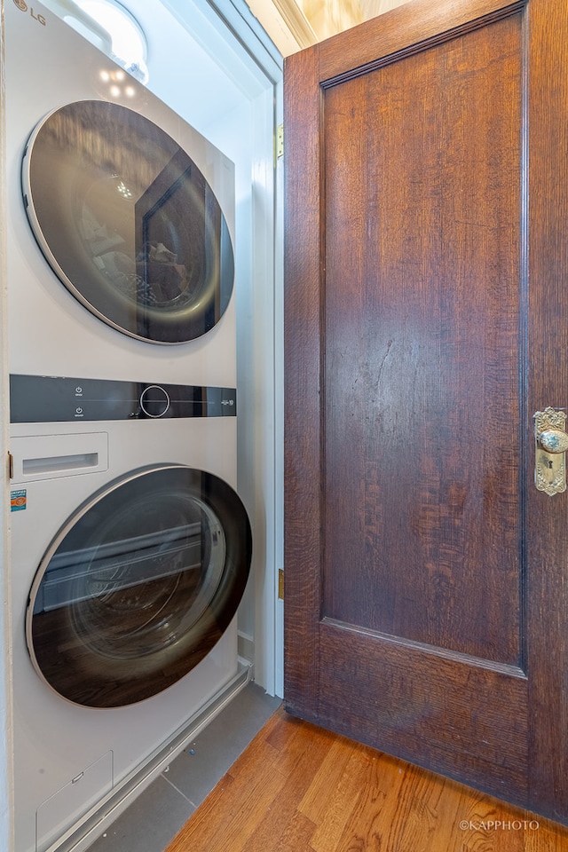 laundry area with light hardwood / wood-style flooring and stacked washing maching and dryer