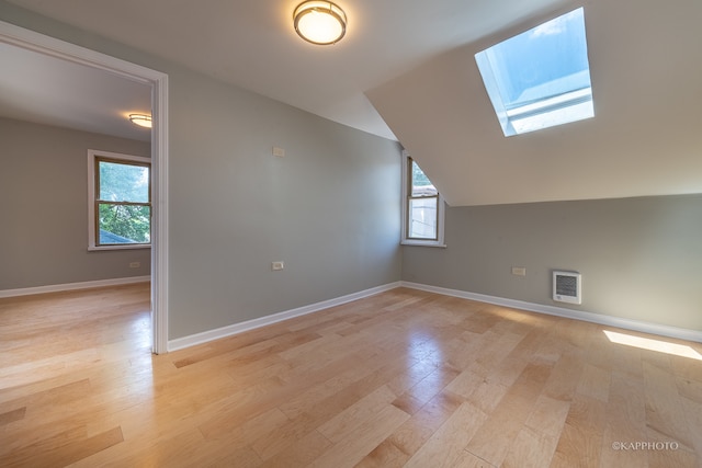 bonus room featuring light hardwood / wood-style flooring, vaulted ceiling with skylight, and plenty of natural light