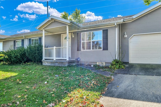 ranch-style house with covered porch, a front yard, and a garage