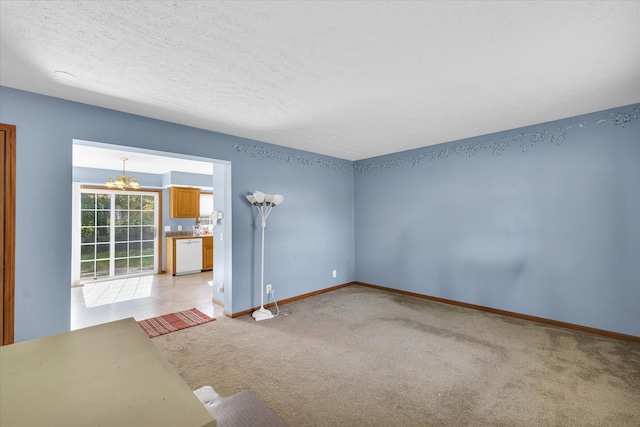 carpeted empty room with a textured ceiling and a chandelier