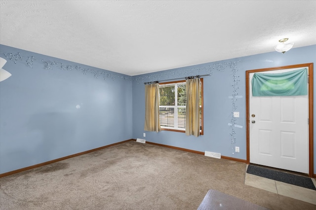 foyer entrance featuring a textured ceiling and light colored carpet