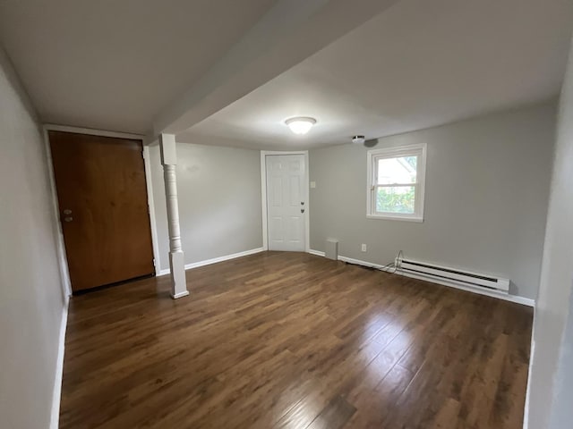 spare room featuring baseboard heating and dark wood-type flooring