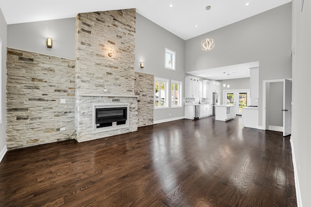 unfurnished living room with sink, a fireplace, french doors, high vaulted ceiling, and hardwood / wood-style flooring