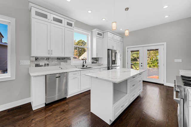 kitchen with pendant lighting, sink, white cabinets, appliances with stainless steel finishes, and a center island