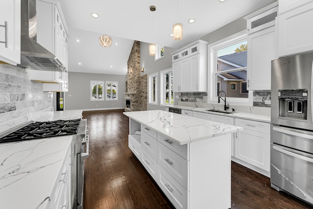 kitchen featuring appliances with stainless steel finishes, wall chimney exhaust hood, white cabinetry, and sink