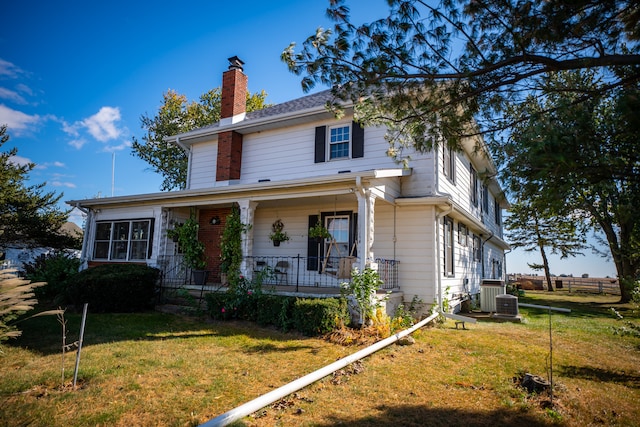 view of front of property featuring a chimney, central AC unit, a porch, and a front yard