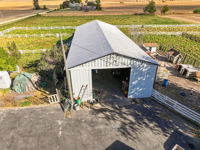 detached garage with a rural view and fence