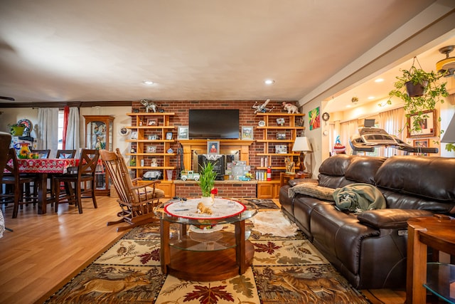 living area featuring brick wall, light wood-style flooring, and a fireplace