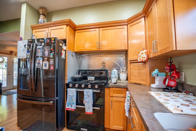 kitchen featuring brown cabinets, light wood finished floors, backsplash, black gas range, and fridge with ice dispenser