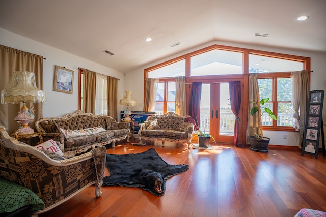 living room with lofted ceiling, visible vents, and wood finished floors