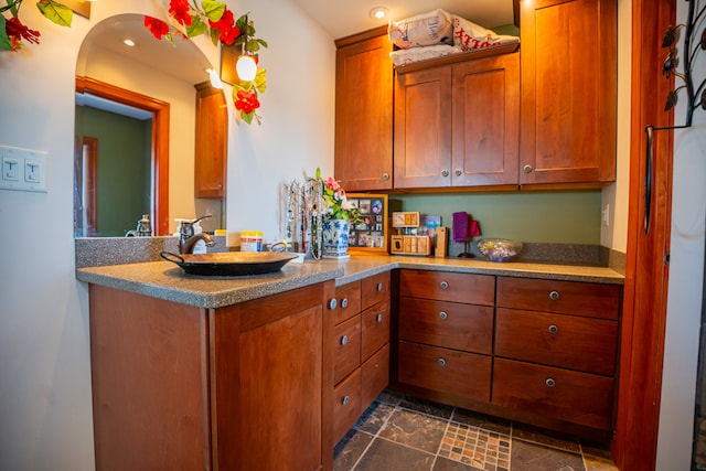 kitchen with arched walkways, brown cabinets, a sink, and a peninsula