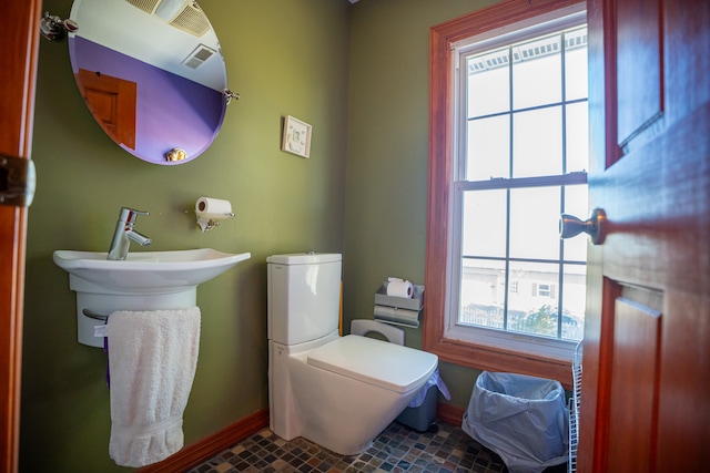 half bath featuring baseboards, visible vents, and toilet