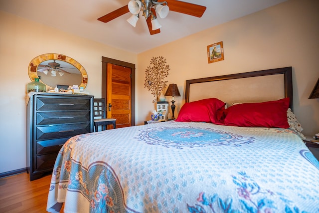 bedroom with ceiling fan, a closet, wood finished floors, and baseboards