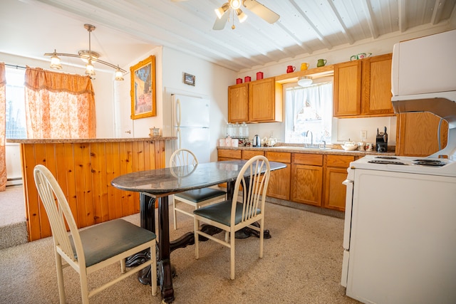 kitchen with brown cabinets, light countertops, a baseboard heating unit, a sink, and white appliances